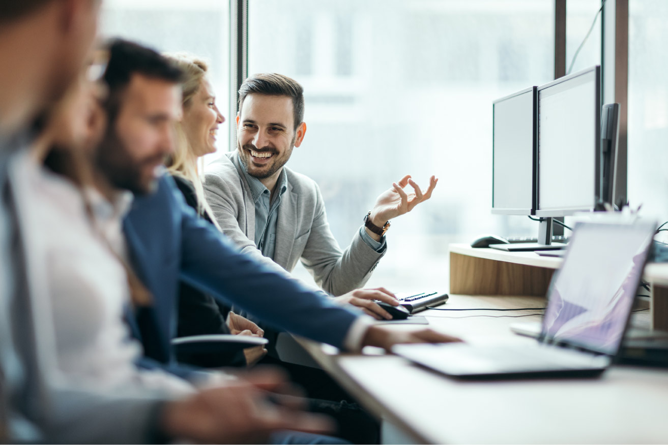 team working and laughing while sitting at the desk with computers